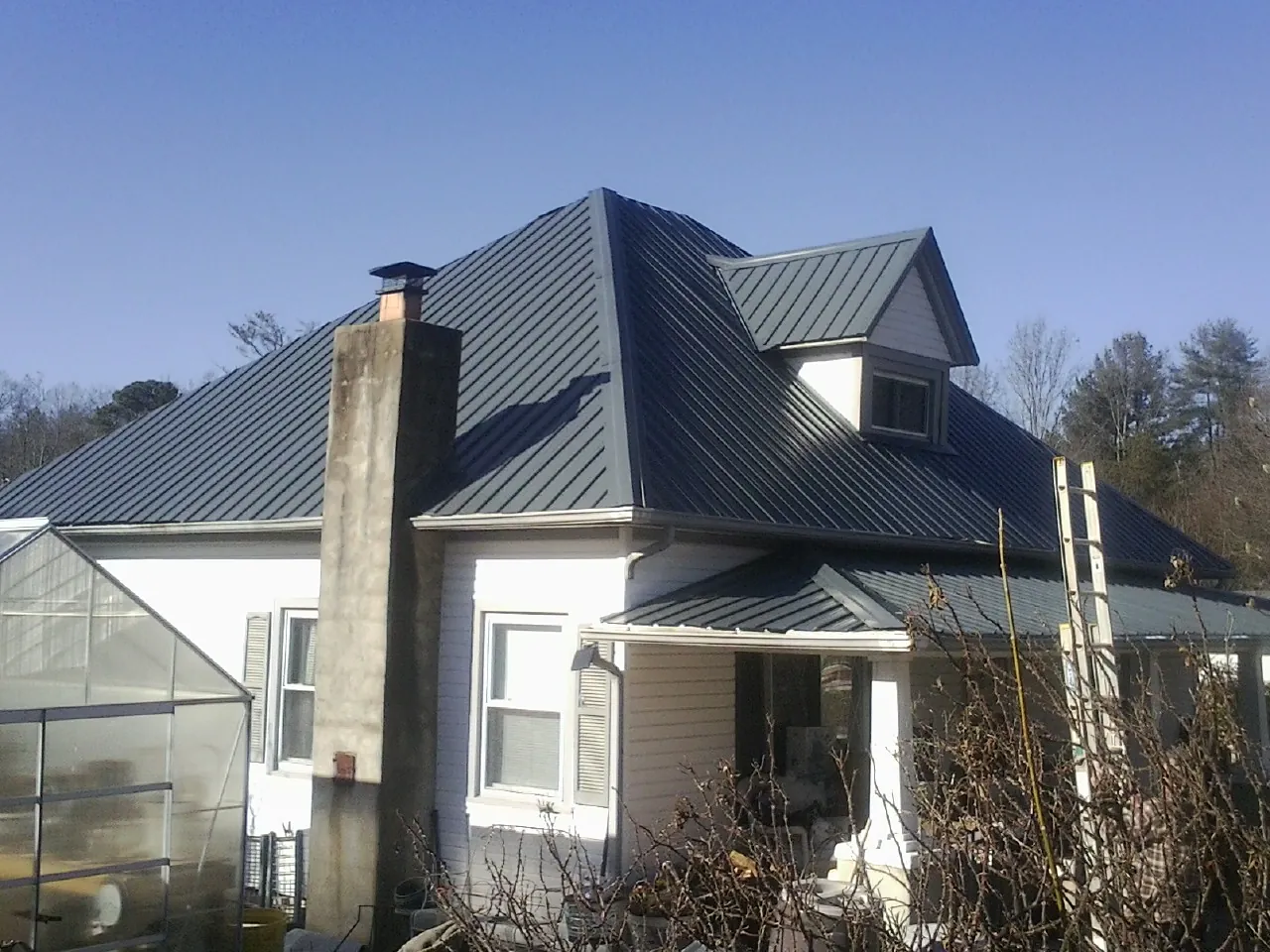 Dark blue standing seam metal roof on a white farmhouse with dormer — Slate & Tile Roof Repair by Roofing Brothers in Blanchester
