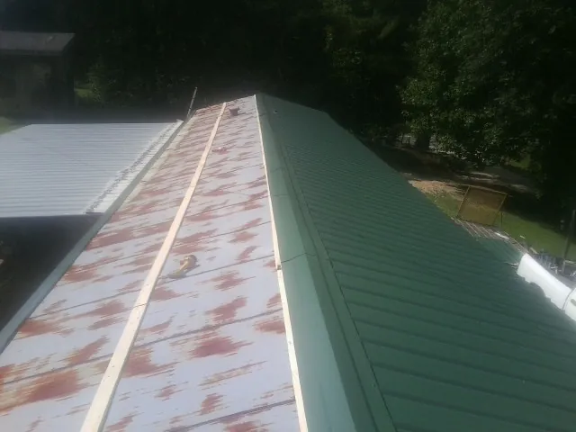 Old rusted panels beside newly installed green metal roofing — Wind Damage Roof Repair by Roofing Brothers in Blanchester