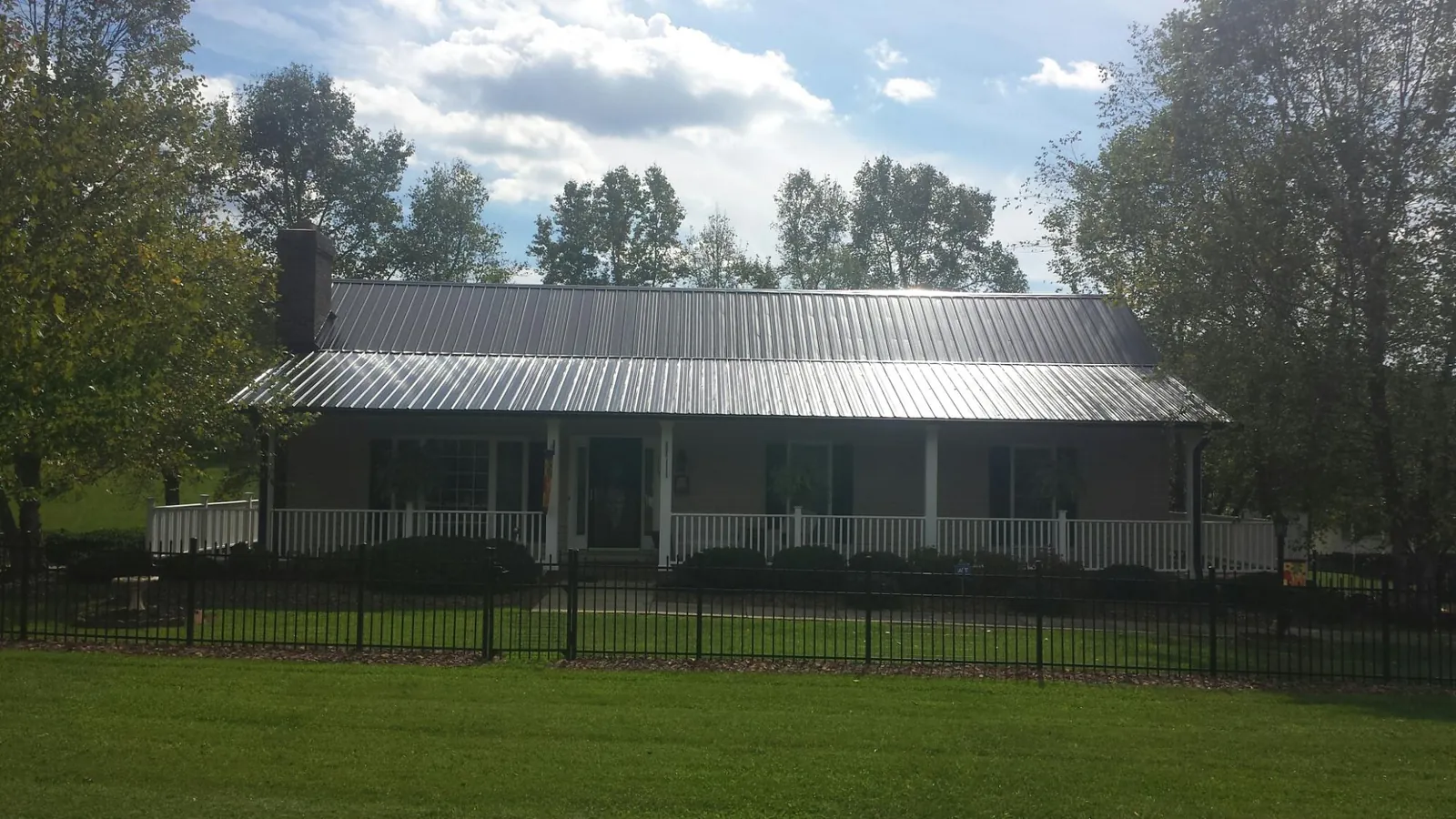 Gray metal roof on a brick ranch with a full width front porch — Gutter Guard Installation work by our crew in Blanchester