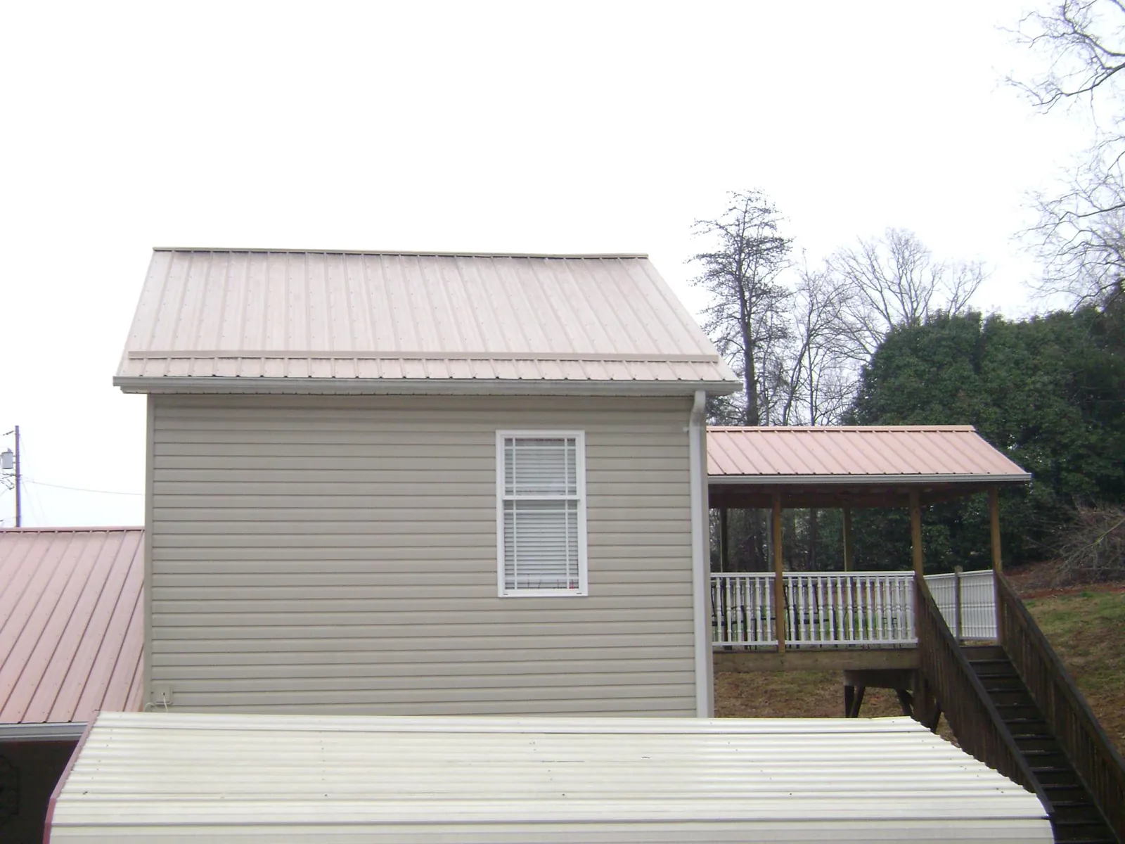 Tan metal roofs on a two story addition and attached porch, from a Roof Replacement job in Blanchester